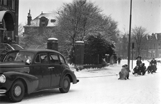 403769 Afbeelding van een groepje kinderen op sleeën die zich door een auto laten voorttrekken over de besneeuwde ...